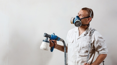 painting contractor wearing mask while painting a wall
